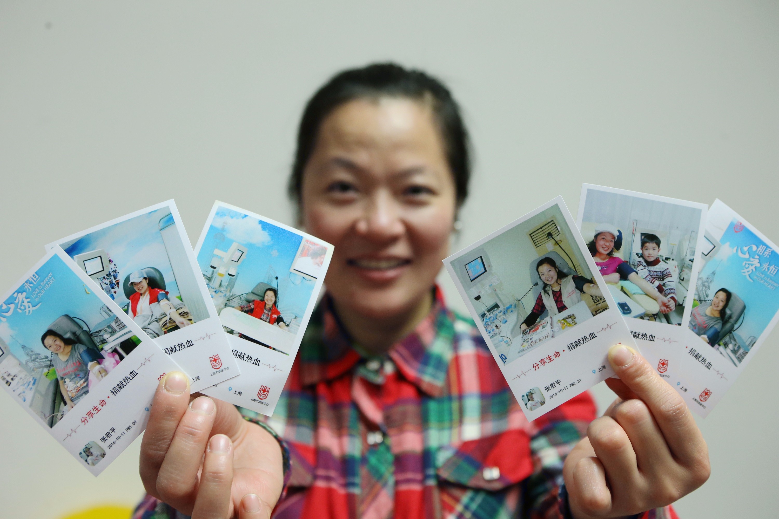 2017年1月19日，上海，张君平展示自己各种时期献血的照片。